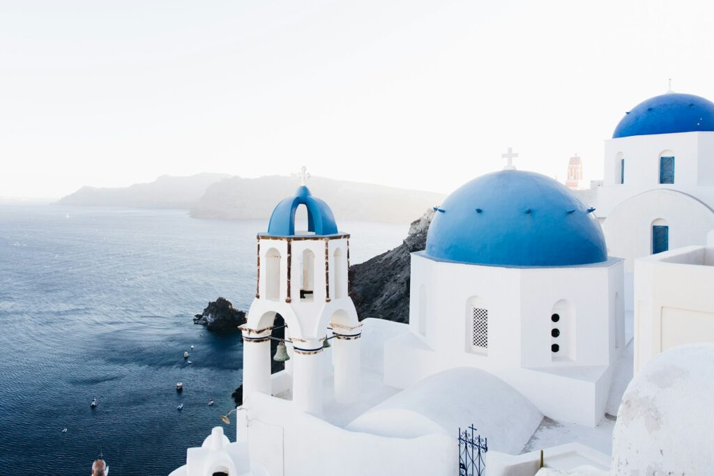 White buildings with blue domes next to the ocean in Santorini